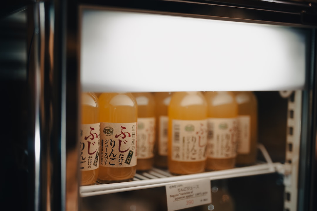 Bottles of Fuji apple juice on a refrigerator shelf, label reads 'ふじ りんご ジュース'.
